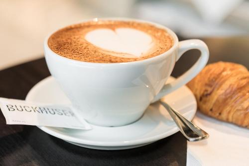 a cup of coffee on a table with a croissant at Placid Hotel Design & Lifestyle Zurich in Zürich