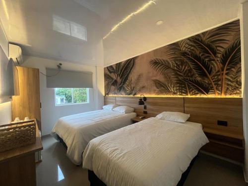 a bedroom with two beds and a painting on the wall at APARTAMENTOS TURISTICOS ALTAMAR in San Andrés