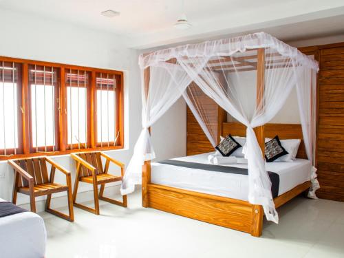 a bedroom with a canopy bed and two chairs at Villa Hima Arana in Galle