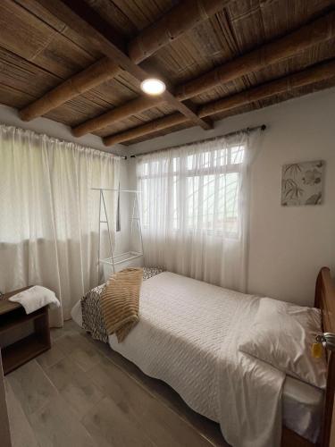 a bedroom with a white bed and a window at Hospedaje Finca Eje Cafetero, Casa Ne u in Marsella