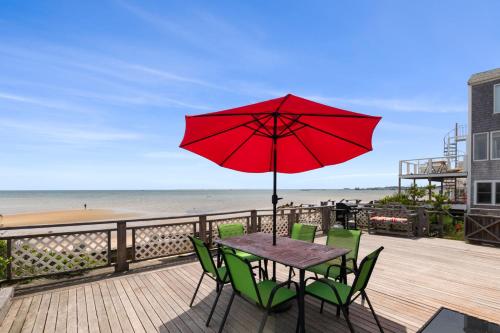 a table with green chairs and a red umbrella on a deck at Beachfront on Commercial St Dog Friendly in Provincetown