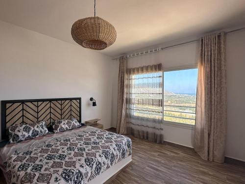 a bedroom with a bed and a large window at Diar Jabal Villa S2 in Banī ‘Aţāʼ