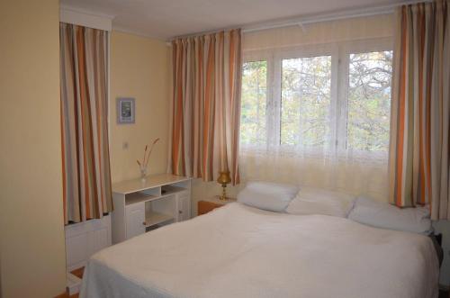 a bedroom with a white bed in front of a window at Casă de oaspeți autentică în Transilvania in Izvoru Mureşului