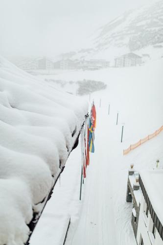 a fence covered in snow with flags on it at Hotel Zürserhof in Zürs am Arlberg