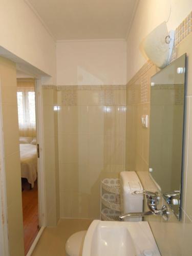 a white bathroom with a sink and a shower at Casă de oaspeți autentică în Transilvania in Izvoru Mureşului