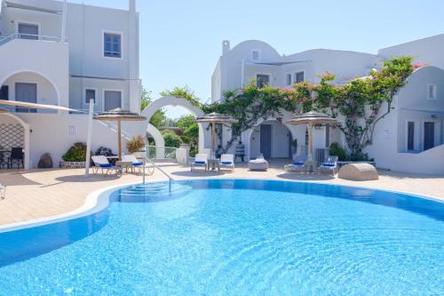 a pool with chairs and umbrellas next to a building at Smaragdi in Perivolos
