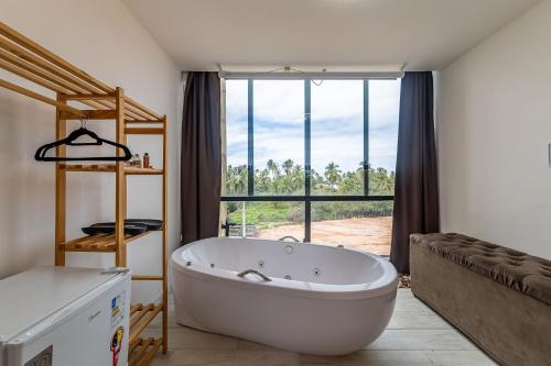 a large white bath tub in a room with a window at Casa inteligente com 4 suítes e piscina - 160D in Japaratinga