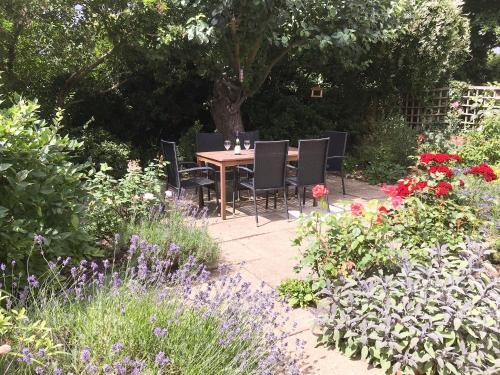 a table and chairs in a garden with flowers at Red Lion Corner in Lavenham