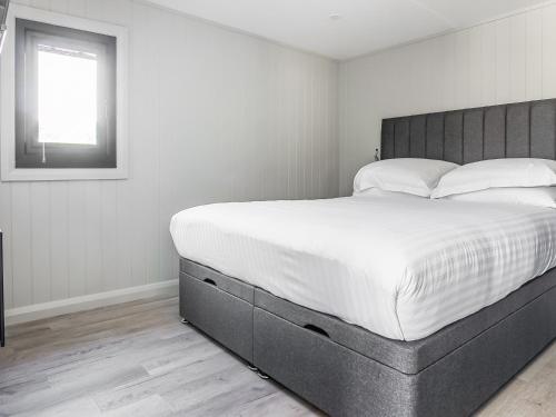 a bedroom with a large bed with white sheets and a window at Mandarin Lodge - Uk51936 in Yarm
