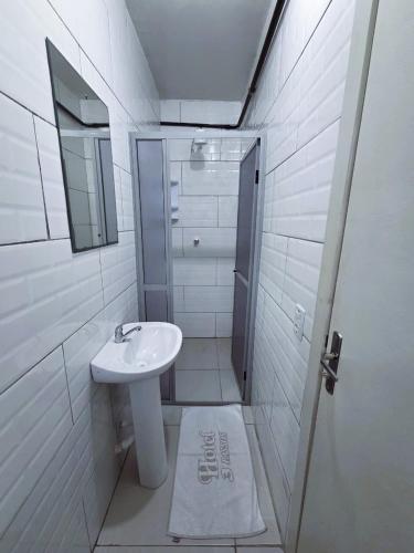 a white bathroom with a sink and a mirror at Hotel Três Passos - Prox ao Aeroporto e Rodoviária in Porto Alegre