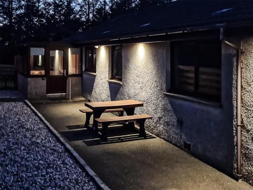 a wooden bench sitting in front of a building at Lowesmuir Cottage in Cumnock