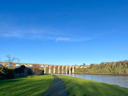 a bridge over a river with green grass and a road at Royal Border Retreat in Berwick-Upon-Tweed