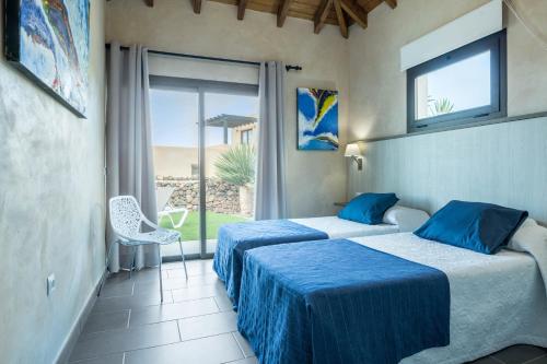 two beds in a room with a view of the ocean at Villa La Era 2 in El Cotillo