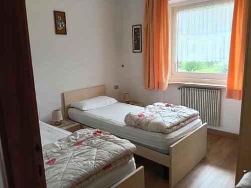 two beds in a small room with a window at Casa Defrancesco - with Garden in Moena