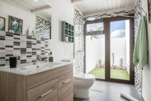a bathroom with a toilet and a sink and a window at Villa La Era 1 in El Cotillo