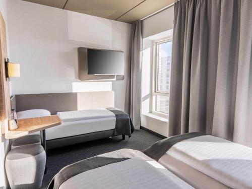 a hotel room with three beds and a window at B&B HOTEL Fürth-Hardhöhe in Fürth