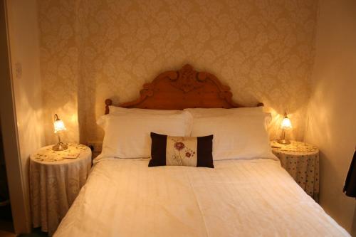 een slaapkamer met een bed met witte lakens en 2 tafels bij School House Cottage B&B and tea garden in Hawkshead