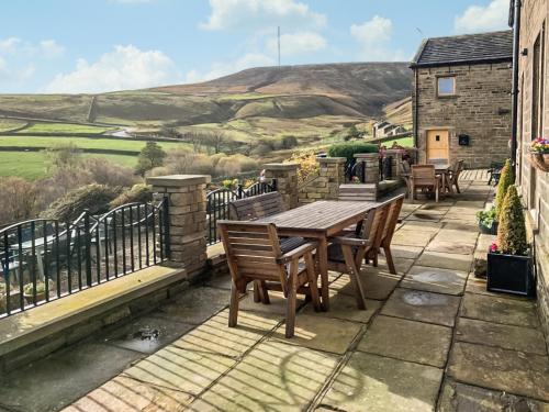 a patio with a wooden table and chairs on a balcony at Trough Cottage - Uk48424 in Holmfirth