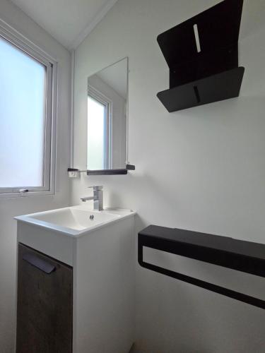 a white bathroom with a sink and a mirror at Camping Val de Boutonne in Saint-Jean-dʼAngély
