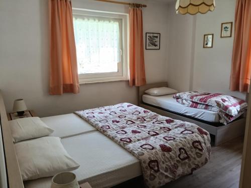 two beds in a small room with a window at Casa Defrancesco - with terrace in Moena