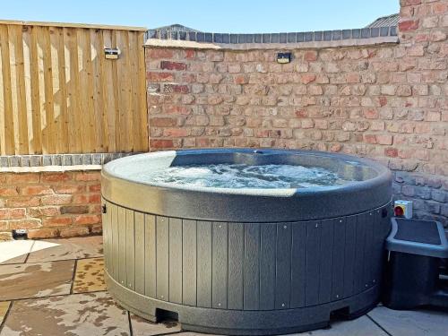 a large hot tub in a yard next to a brick wall at Cart House Barn - Uk49802 in Morville