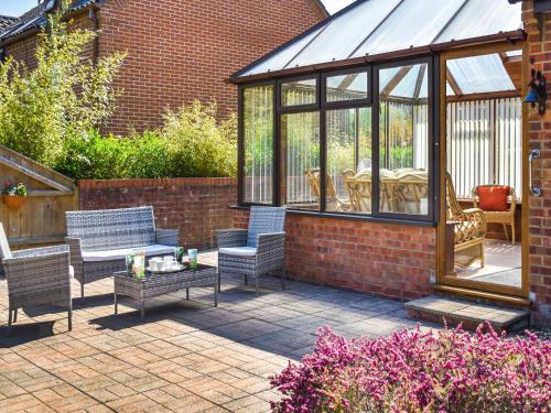 a patio with a conservatory with chairs and a table at Dippers in Smallburgh