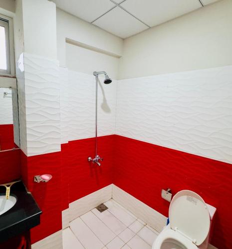a red and white bathroom with a toilet and a sink at Daisy Cottage in Murree