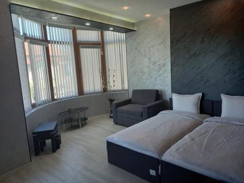 a bedroom with a large bed and a chair at Къща за гости "Адам и Ева" in Kavarna