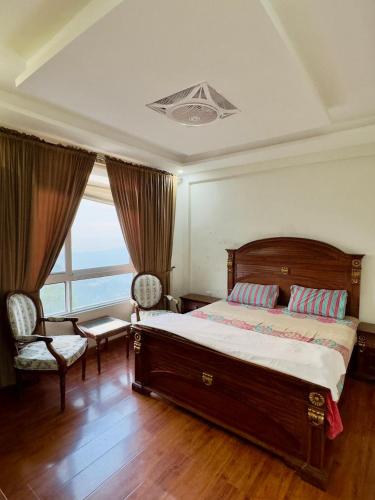 a bedroom with a bed and two chairs and a window at Daisy Cottage in Murree
