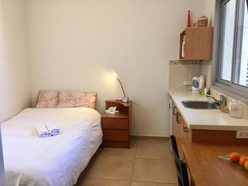 een kleine kamer met een bed en een wastafel bij Kfar Saba Center Apartment in Kefar Sava