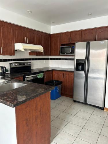 a kitchen with wooden cabinets and a stainless steel refrigerator at HomeNet in Toronto