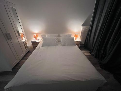 a large white bed in a room with two lamps at Eden-Novia in Orléans