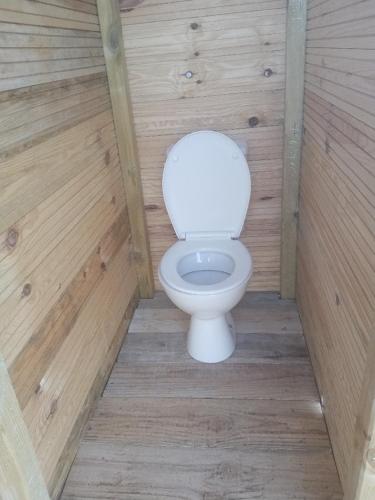 a bathroom with a toilet in a wooden wall at Tente Cocoon in La Brillanne