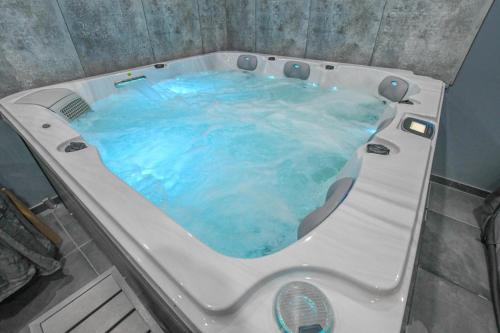 a bath tub with blue water in a bathroom at Le charme du moulin in Beauvoir-sur-Sarce