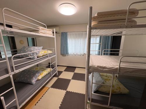 a room with two bunk beds and a checkered floor at Outdoor Station 秋谷 in Yokosuka