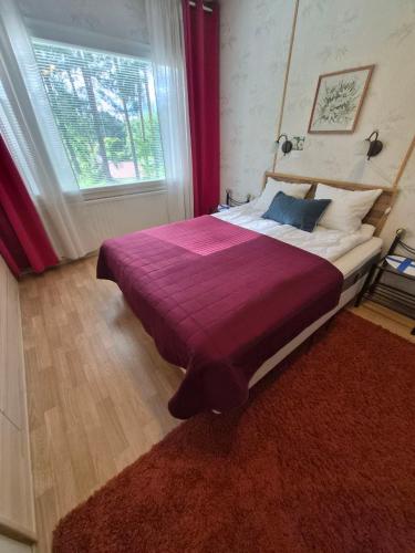 a bedroom with a large bed with a red blanket at MiniMani House with Sauna in Sorsakoski
