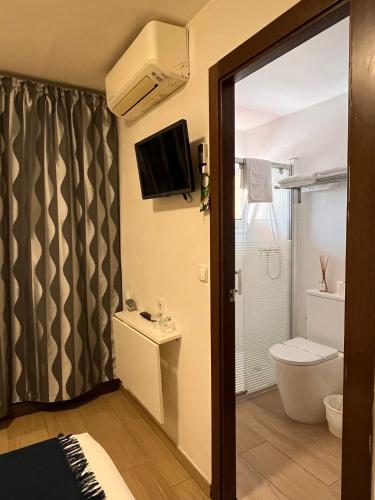 a bathroom with a toilet and a tv on the wall at Hostal Cubelles in Cubelles
