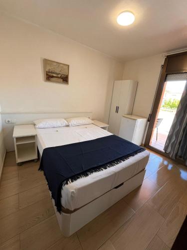 a bedroom with a large bed and a refrigerator at Hostal Cubelles in Cubelles