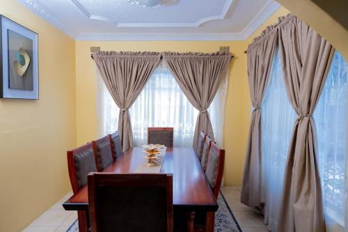 a dining room with a wooden table and curtains at Mainway home in Harare
