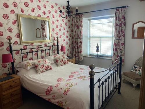 a bedroom with a bed with pink floral wallpaper at Middle Cottage in Middleham