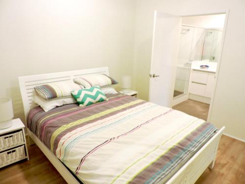biała sypialnia z łóżkiem z poduszkami i lustrem w obiekcie Contemporary Cove - Quindalup w mieście Quindalup