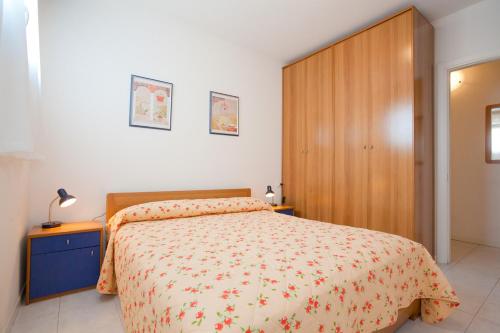 1 dormitorio con cama y armario de madera en Colombo Apart-Hotel 4 Stars Luxury with swimming Pools on the roof where you can see the Sea and with covered parking space, en Caorle