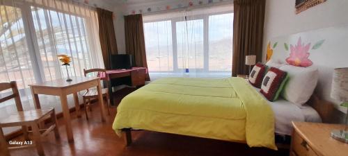 a bedroom with a yellow bed and a table and chairs at Kurumi Hostel in Cusco
