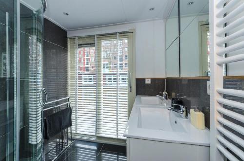 baño con lavabo, espejo y ventana en The Guest-Houseboat, en Ámsterdam