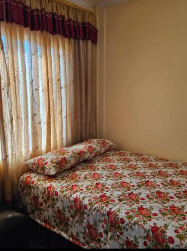 a bedroom with a bed with a flowered blanket and a window at Peace and Quiet accomodation in Richards Bay