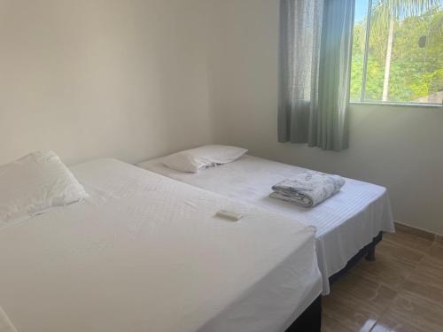 two twin beds in a room with a window at Red Coral Apts in Coroa Vermelha