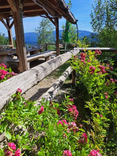 a wooden bench in a garden with pink flowers at Glamping Gril in Ljubno