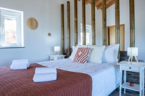 a bedroom with a large white bed and a window at Quinta da Barradinha in Odemira