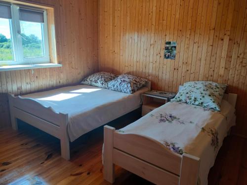 two beds in a room with wooden walls and a window at Білий лебідь in Pulemets