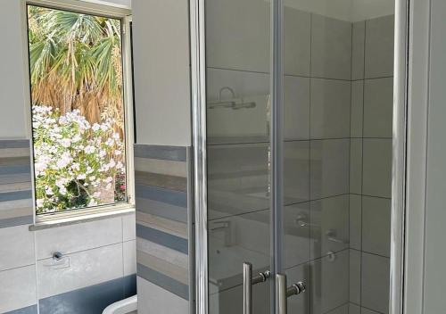 a bathroom with a shower and a toilet and a window at EmmeBi Appartamenti in Acquedolci